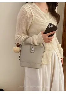 Detail of beige bucket bag with lychee texture, silver twist lock and plush charm