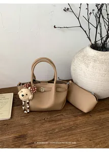 Close-up of brown pebbled leather bucket bag with plush dog charm and mini pouch