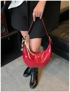 Detail of red crescent bag with glossy finish and braided rope charm accessory