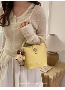 Detailed shot of yellow bucket bag with plush bear charm and beaded ornament
