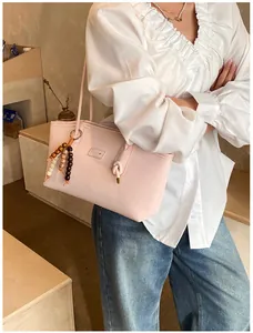 Close-up of a pink tote bag with beaded tassel charm on a model in white blouse