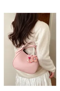Sac seau rose grainé orné d'une breloque de perles et d'une fleur tricotée à la main