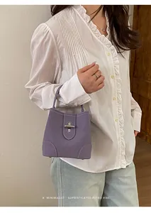 Detail of purple bucket bag with white contrast stitching and silver turn-lock closure