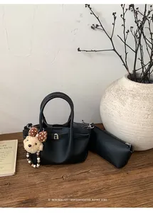 Detail of black pebbled leather bucket bag with cute bear charm and matching pouch