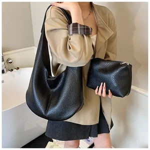 Detail of black pebbled leather hobo bag and matching pouch set worn by a model