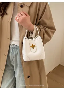 Detail of white lychee leather bucket bag featuring a minimalist golden cross twist lock