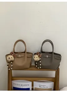 Detail of minimalist leather bucket bags in khaki and coffee with cute bear charms