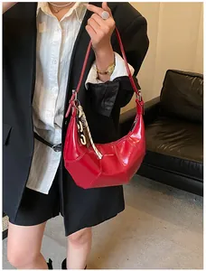Detail of red glossy leather hobo bag with logo and stylish chain accessory