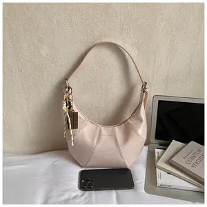 Detailed view of beige hobo bag with chocolate charm and textured leather stitching