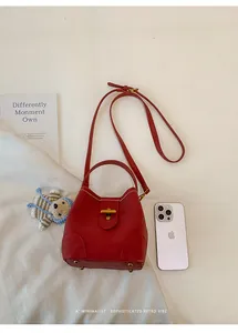 Top view of red lychee pattern bucket bag with golden metal twist lock and shoulder strap