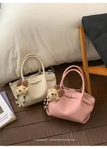 Detail of minimalist bucket bag in cream and pink with pebbled texture and cute charms