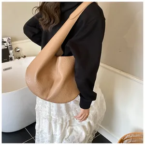 Minimalist caramel hobo bag with wide shoulder strap styled in a modern interior setting