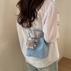 Chic light blue lychee pattern bucket bag with cute bear charm worn by a model
