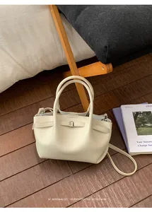Detailed macro view of cream litchi grain leather bucket bag with silver twist lock closure