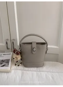 Detail of grey textured leather bucket bag with silver twist lock and plush bear charm