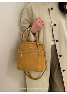 Detailansicht der senfgelben Ledertasche mit geprägten Buchstaben und Doppelgriffen