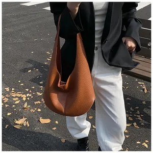 Minimalist brown lychee leather hobo bag worn by a model in a professional urban setting