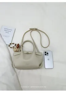 Top view of beige bucket bag with plush dog charm and shoulder strap on white fabric
