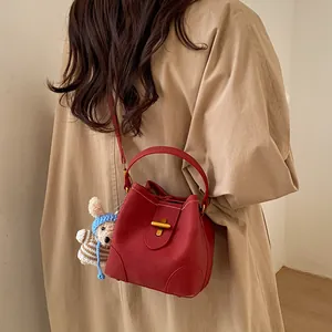 Deep red leather bucket bag with gold cross lock and cute rabbit plush charm