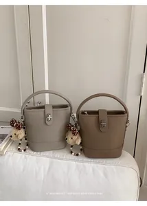 Detail of retro bucket bags in beige and brown with plush puppy charms and metal locks