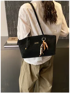 Detail of black matte leather tote bag with vintage wood bead charm and gold logo