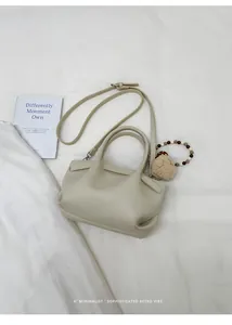 Close-up of cream leather bucket bag with pebble texture and cute pompom charm detail