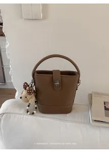Detailed shot of a brown bucket bag with lychee texture and cute bear pendant charm