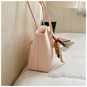 Close-up of pale pink tote bag with bohemian beaded charm and slim shoulder straps