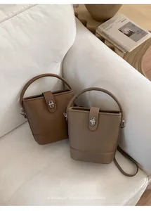 Close-up of litchi texture leather bucket bags with metal rotary locks and top handles