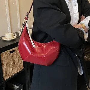 Polished bright red crescent shoulder bag with metallic chain and geometric stitching