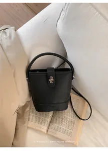 Detail of black pebbled leather bucket bag with metal twist lock on an open book