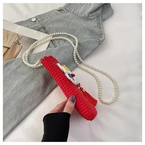 Close-up of red crochet knitted bag with festive fringe and pearl shoulder strap