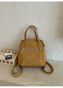 Detail des senfgelben Rucksacks mit geprägten Buchstaben und silbernem Metallreißverschluss