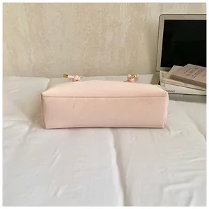 Detail of light pink tote bag showing reinforced base stitching and knotted strap hardware