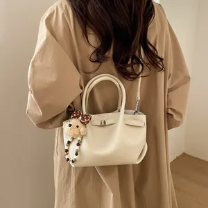 Chic beige lychee pattern bucket bag with cute bear charm and adjustable strap