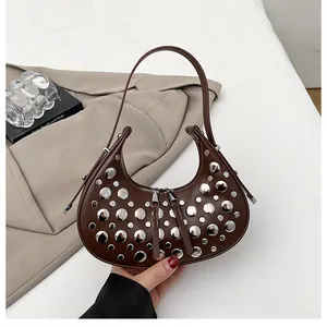 Close-up of a dark brown crescent hobo bag featuring silver rivets and dual zipper design