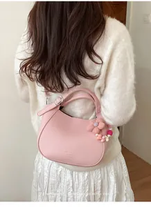 Sac seau en cuir grainé rose avec charme floral porté par un mannequin en tenue blanche