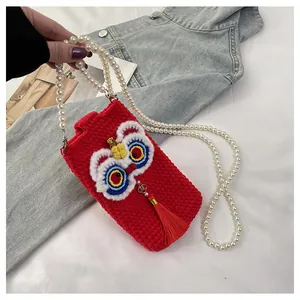 Detailed knit of red lion dance phone bag with pearl strap and festive red tassel detail