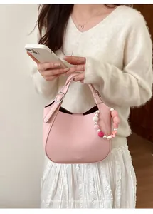 Sac seau rose à grain litchi avec breloques perles et pompons porté par un mannequin