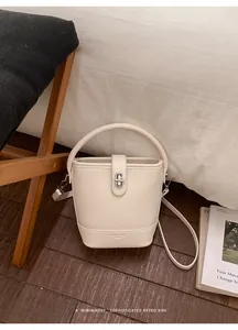 Close-up of creamy white bucket bag featuring pebble grain texture and silver swivel lock