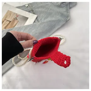 Detail view of red knitted bag showing thick yarn texture and elegant pearl shoulder strap