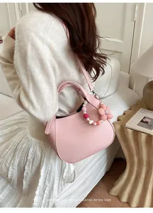 Vue détaillée du sac hobo en cuir rose avec breloque fleur et détails perlés