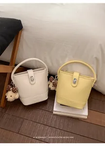 Detail view of two bucket bags in cream and yellow colors with cute bear pendants