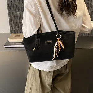 Minimalist black suede tote bag with boho bead charm shown in a daily lifestyle setting
