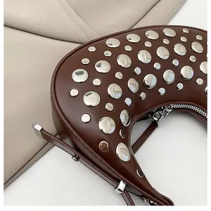 Detail of chocolate brown leather crescent bag with silver metallic studs and zipper