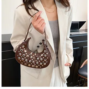 Detail of a brown leather crescent shoulder bag with silver studs and double zipper
