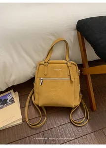 Detail eines ingwergelben Lederrucksacks mit Buchstabenprägung und Silberreißverschluss