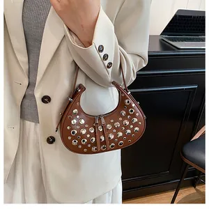 Close-up of brown leather crescent bag featuring stylish silver metal rivet decorations