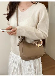 Détail du sac hobo kaki avec breloque florale et bandoulière sur une femme mannequin