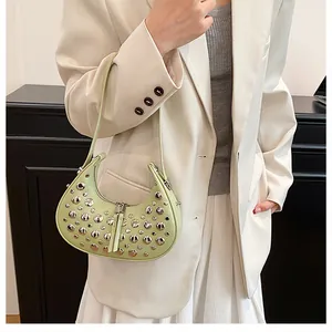 Detail of light green crescent underarm bag with silver rivets on matte leather